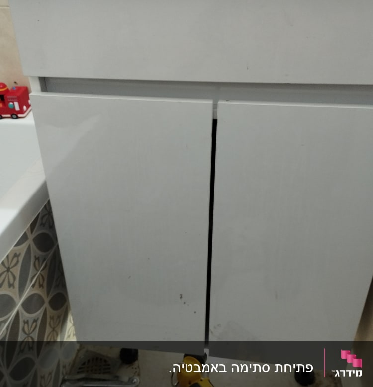 ארון אמבטיה פתוח עם מקדחה על הרצפה